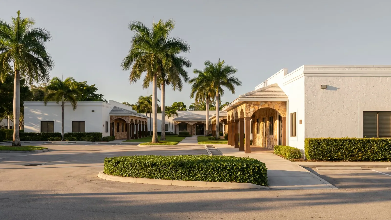 A low-rise medical office plaza with royal palms in Boca Raton in late afternoon sun.