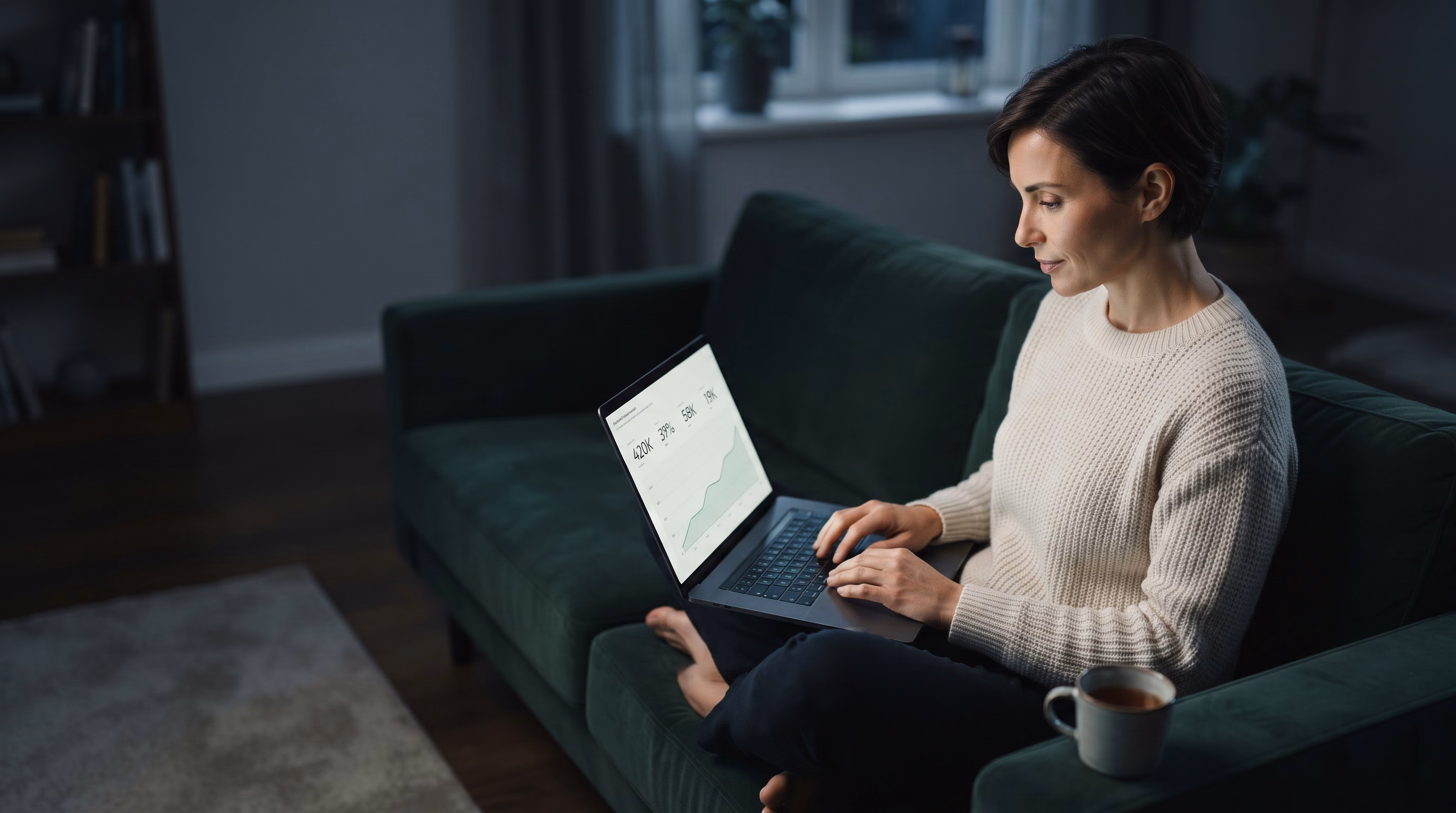 A business owner on a sofa reading a one-page monthly report on a laptop